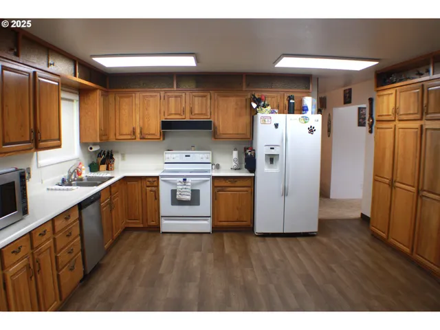a kitchen with stainless steel appliances a refrigerator a sink a stove a microwave and wooden floors