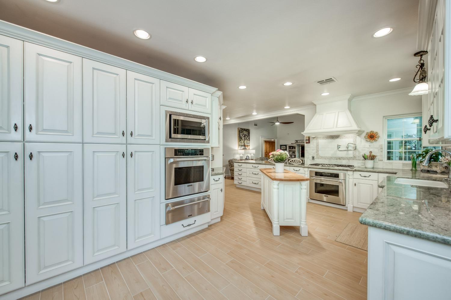 2988 Enterprise Avenue Clovis, CA 93619 - Photo 70 of 99 a kitchen with stainless steel appliances granite countertop a refrigerator oven a sink dishwasher and white cabinets with wooden floor