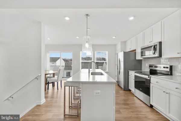 a large kitchen with kitchen island a large counter space a sink appliances and cabinets