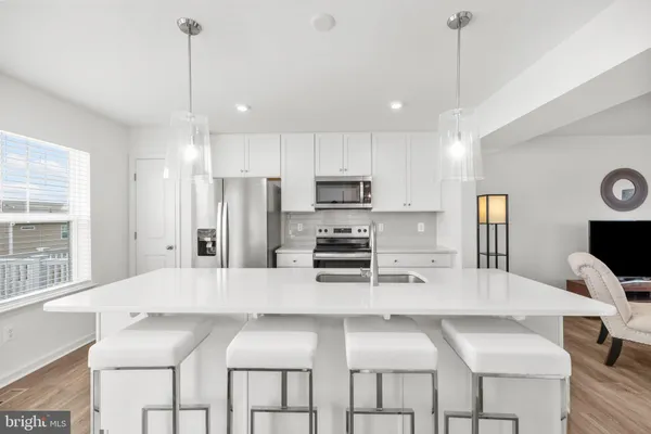 a kitchen with stainless steel appliances granite countertop a sink a stove a refrigerator cabinets and chairs