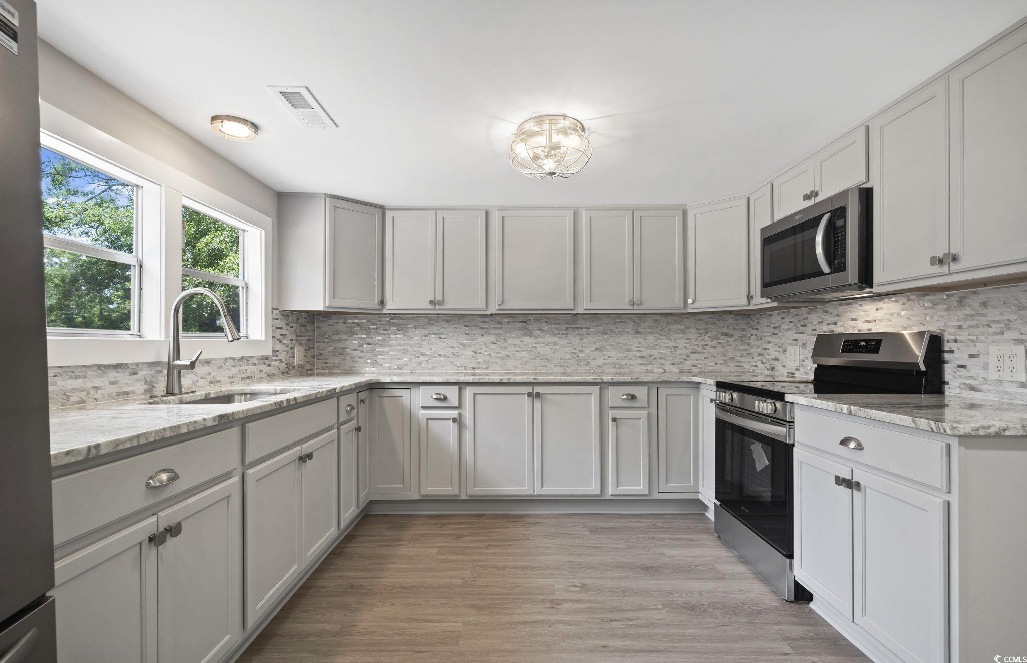 2074 Jem Lane Conway, SC 29527 - Photo 5 of 15 Kitchen featuring appliances with stainless steel finishes, decorative backsplash, light stone countertops, light wood-style floors, and gray cabinetry
