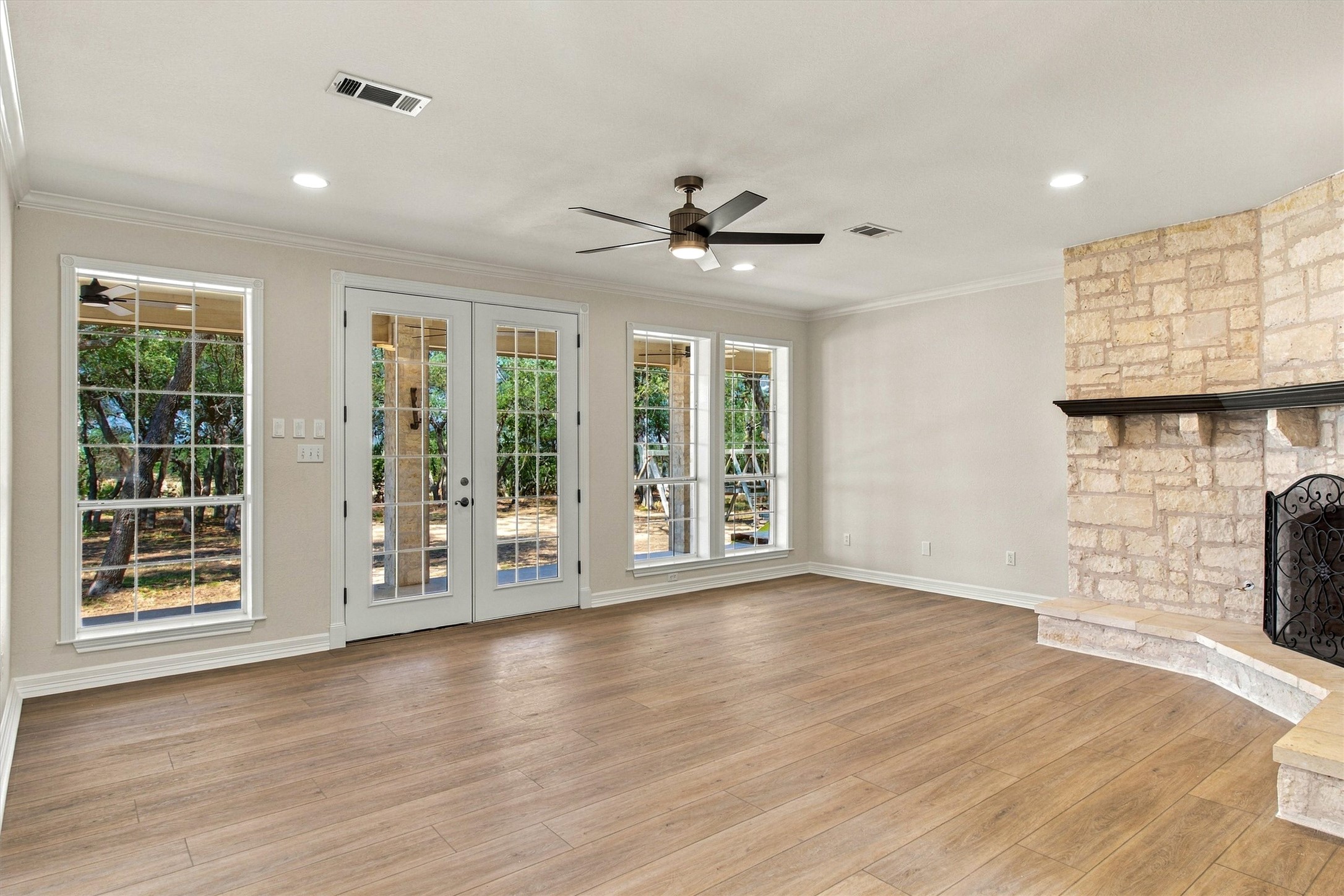 1651 Old Red Ranch Road Dripping Springs, TX 78620 - Photo 4 of 31 A stone fireplace anchors this living space accented by wood flooring and French doors.
