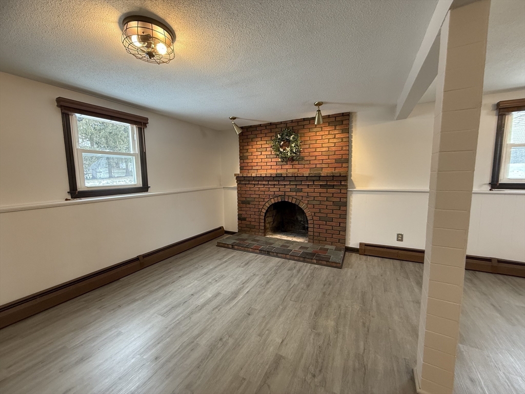 63 Helene Street Ludlow, MA 01056 - Photo 11 of 11 an empty room with wooden floor a fireplace and windows