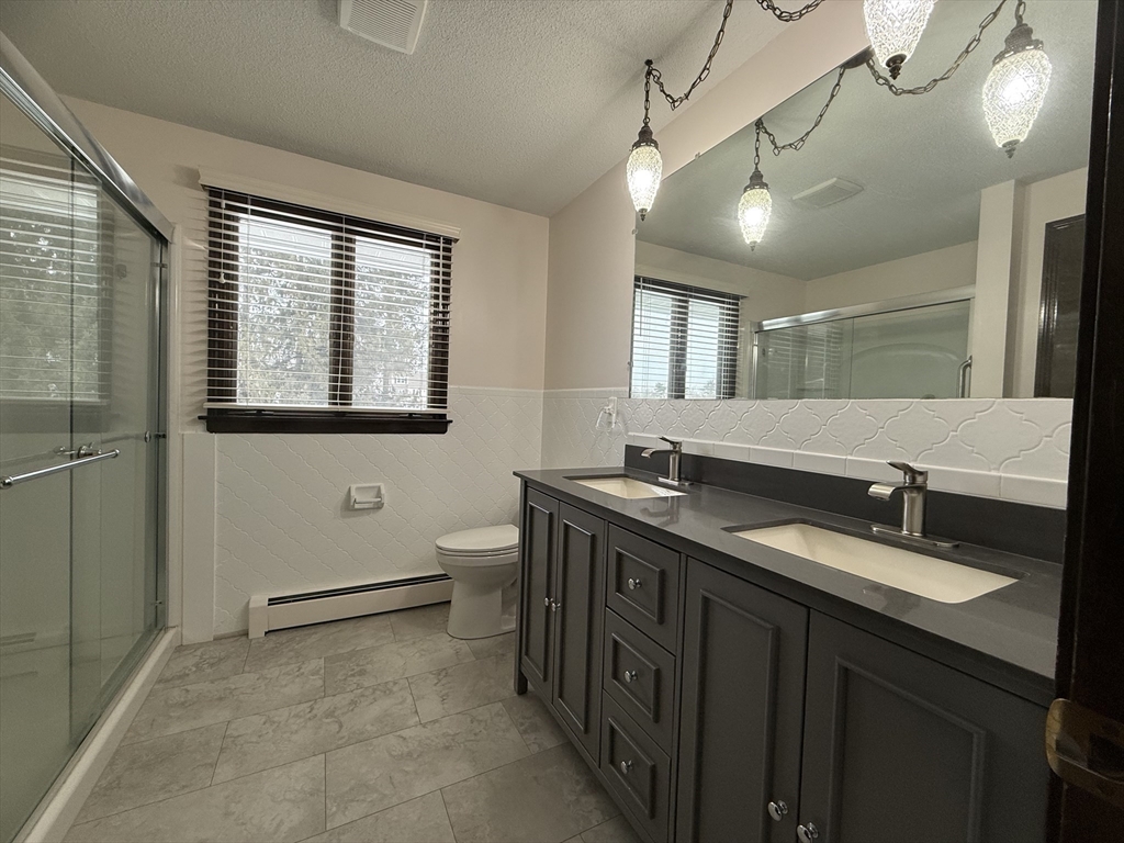 63 Helene Street Ludlow, MA 01056 - Photo 3 of 11 a bathroom with a granite countertop sink a toilet a mirror and a window