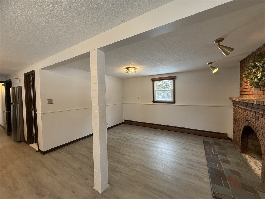 63 Helene Street Ludlow, MA 01056 - Photo 10 of 11 an empty room with wooden floor fireplace and windows
