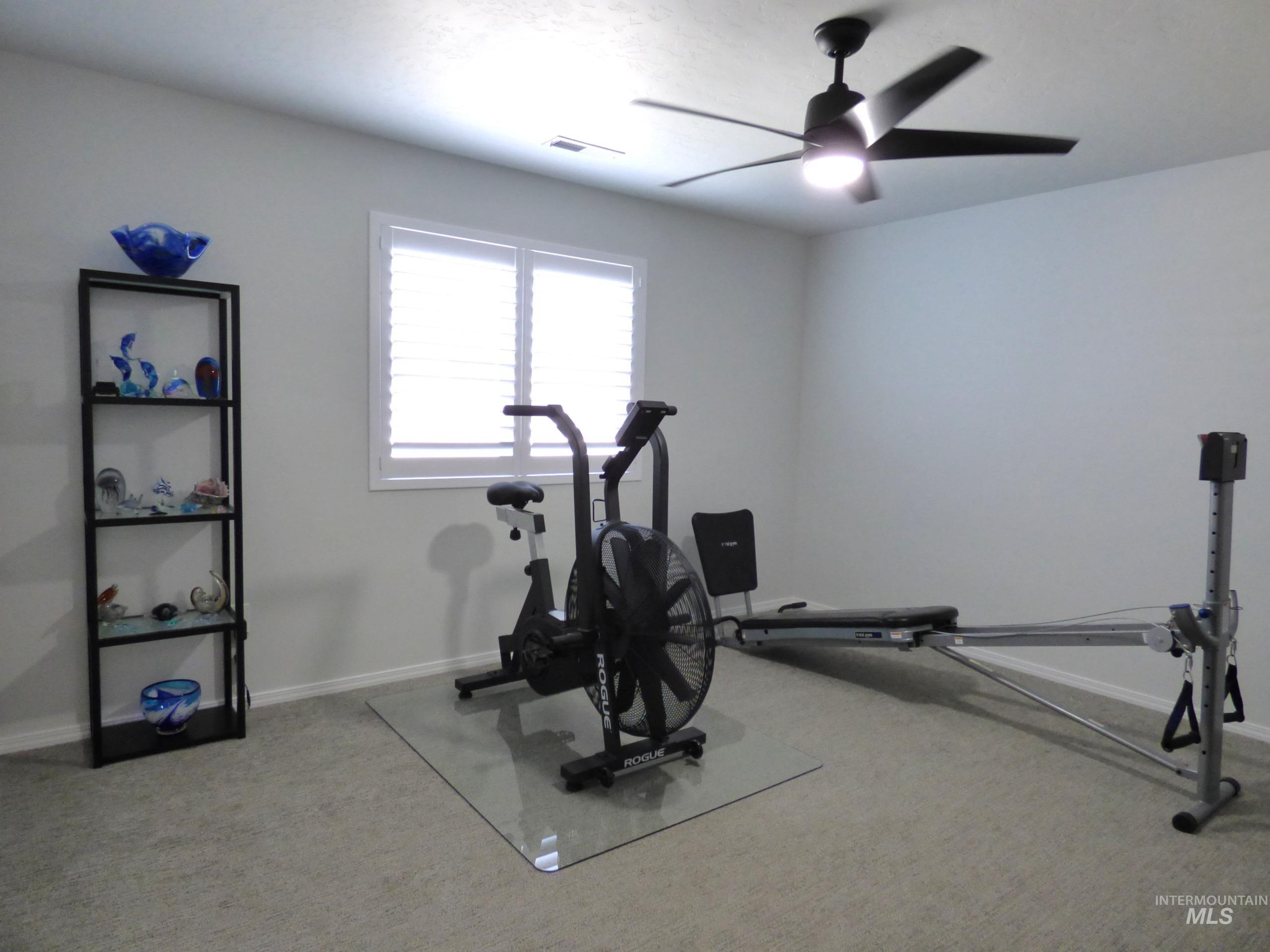 2708 East Buckaroo Drive Kuna, ID 83634 - Photo 26 of 48 Spacious room featuring light gray carpeting, a window with white plantation shutters, and a ceiling fan with integrated lighting