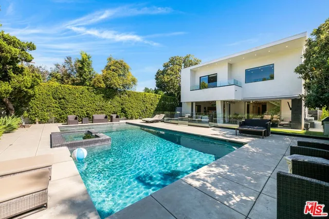 a view of swimming pool with lawn chairs and plants