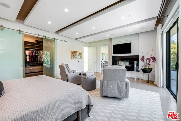 a bedroom with furniture a flat screen tv and a book shelf