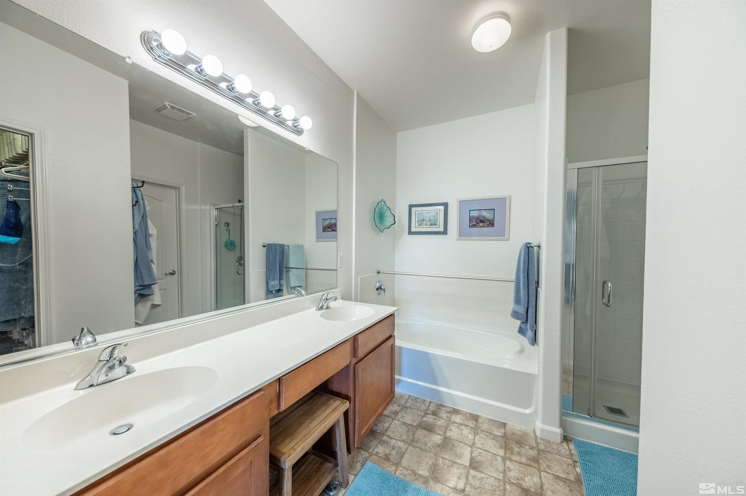 9050 Double R Boulevard, Unit 1925 Reno, NV 89521 - Photo 15 of 32 a spacious bathroom with a double vanity sink a large mirror and a bathtub