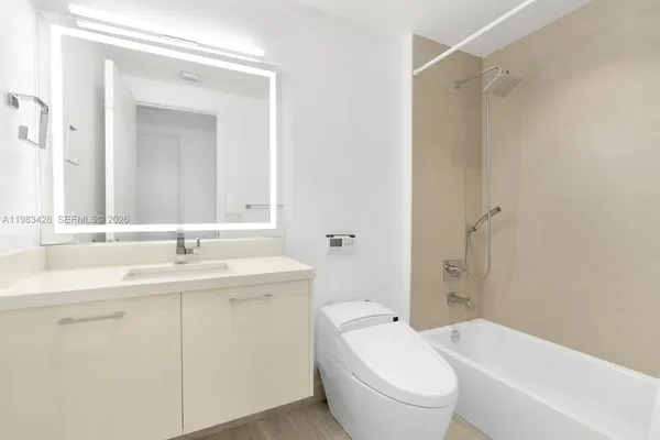 a bathroom with a toilet a sink a mirror a bathtub and shower