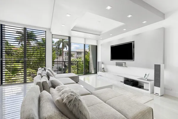 a living room with furniture a flat screen tv and a floor to ceiling window