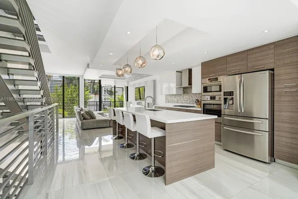 a kitchen with stainless steel appliances a stove a refrigerator a dining table and chairs with wooden floor