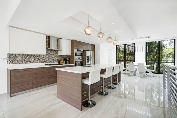 a large white kitchen with kitchen island a large island in the center
