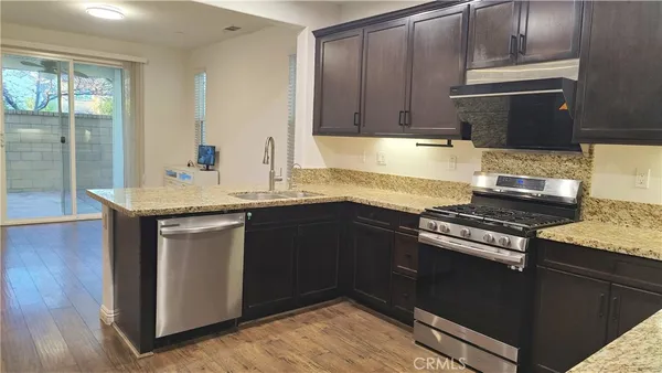 a kitchen with granite countertop a sink cabinets and stainless steel appliances