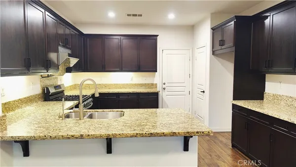 a kitchen with kitchen island granite countertop wooden cabinets and sink