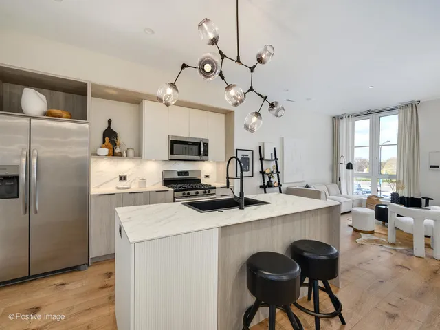 a kitchen with a refrigerator a stove a sink and chairs