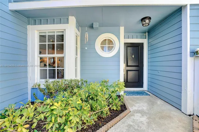a front view of a house with a large window and flower plants
