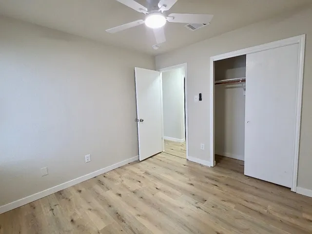an empty room with wooden floor and closet area