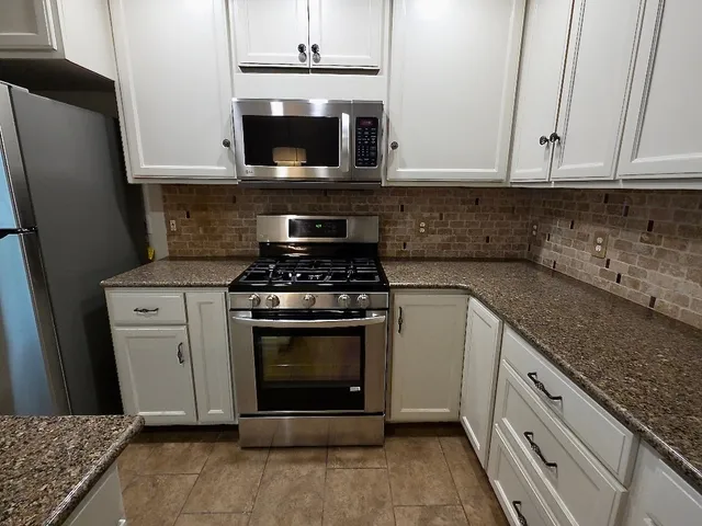 a kitchen with stainless steel appliances granite countertop a stove microwave and refrigerator