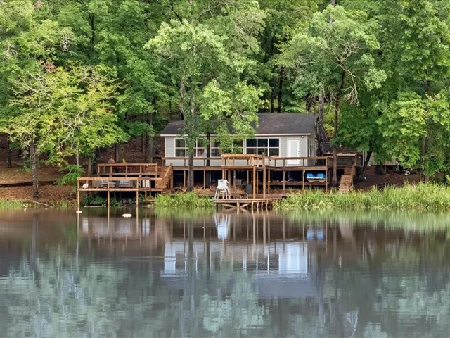 a view of house with river and trees in the background