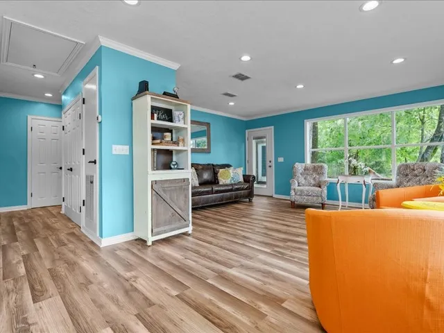 a living room with furniture a large window and wooden floor