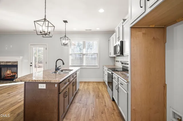 a view of an empty room with wooden floor fireplace and a window