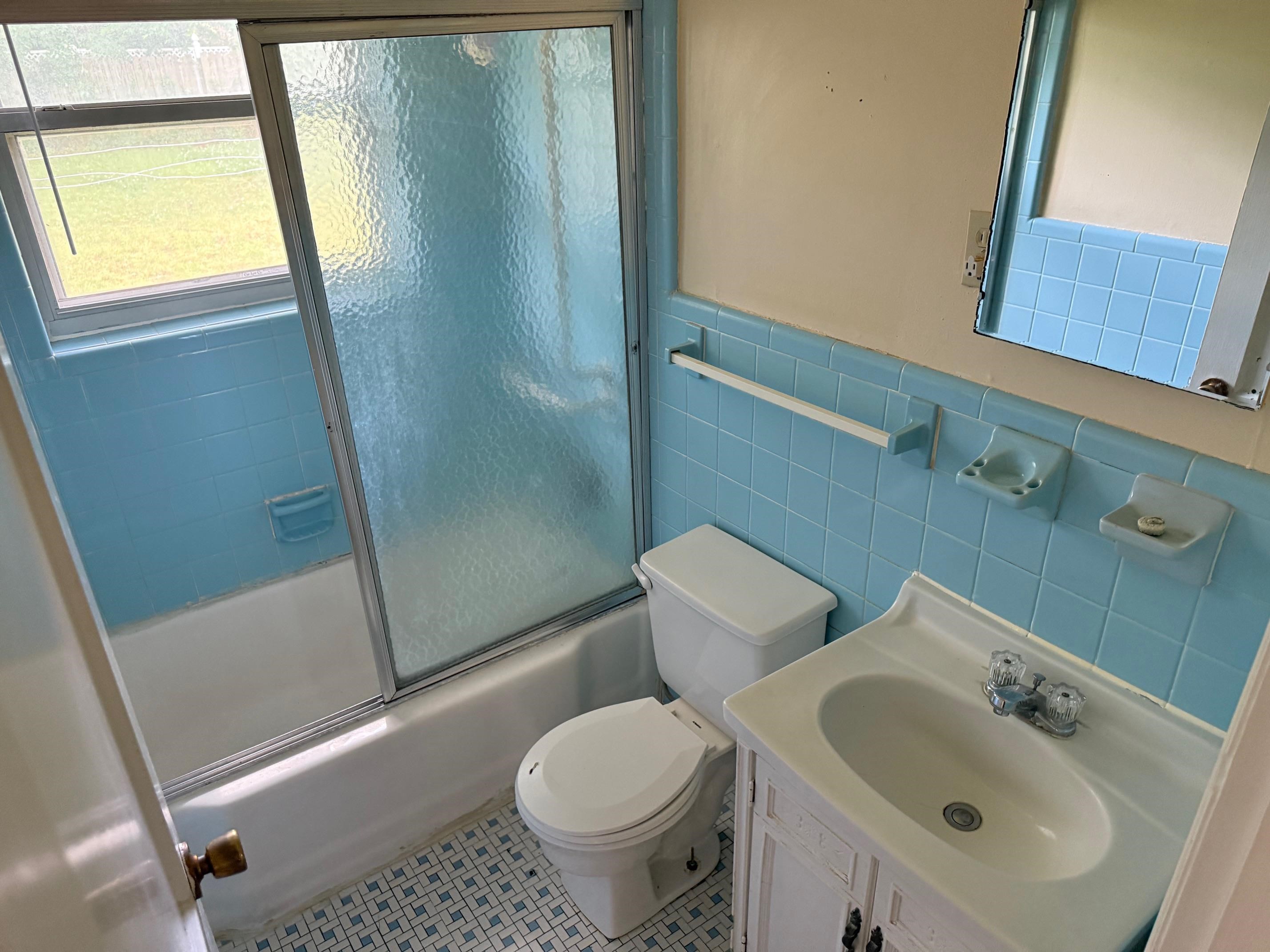 4519 Quince Road Memphis, TN 38117 - Photo 4 of 7 Full bath featuring toilet, shower / bath combination with glass door, tile walls, vanity, and wainscoting