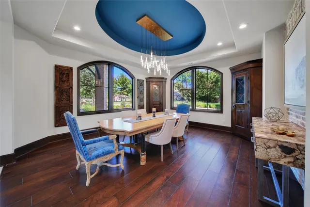 a dining room with wooden floor a chandelier a wooden table and chairs