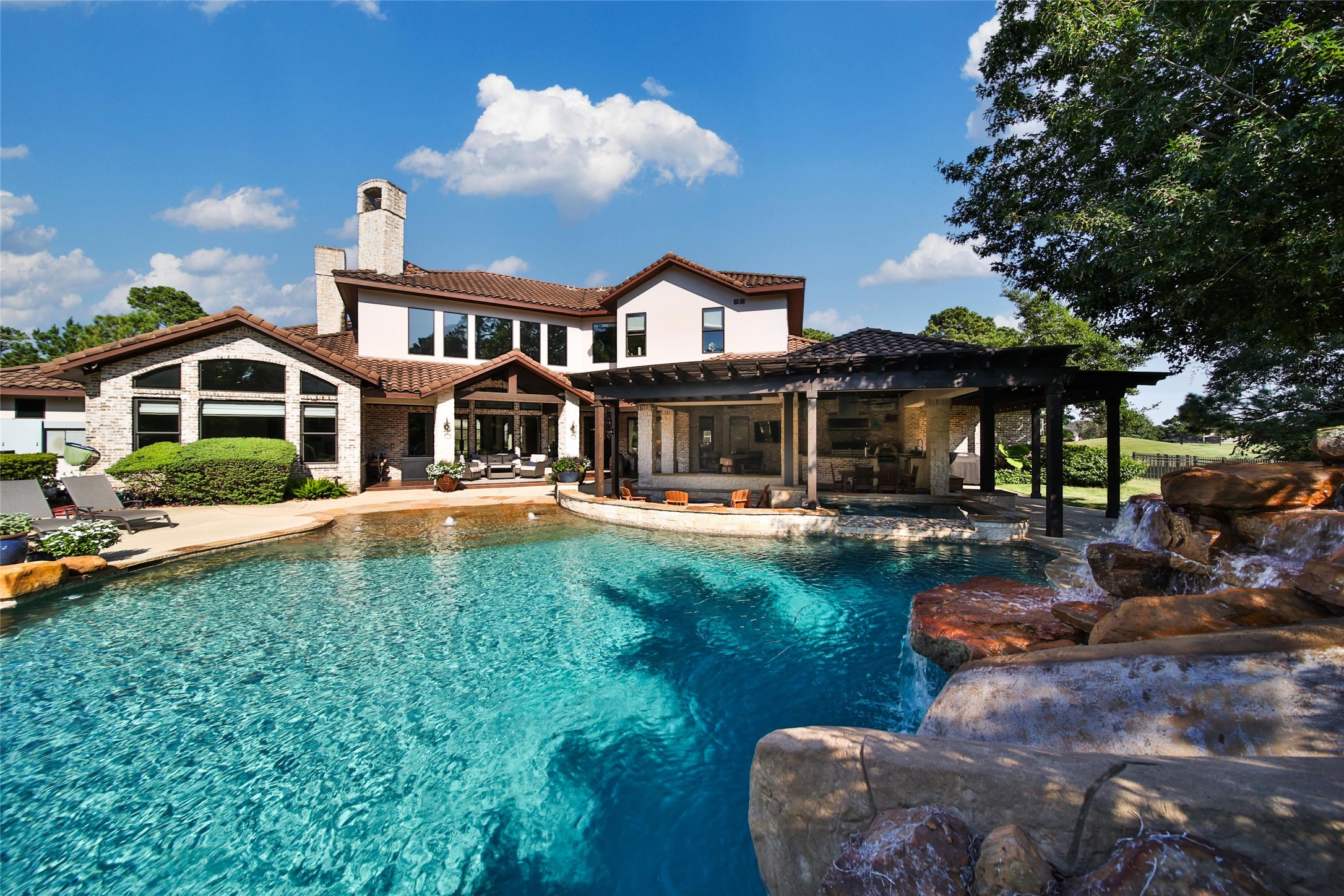 2 Highclere Park Drive Spring, TX 77379 - Photo 2 of 50 Your backyard is an outdoor oasis that's easy to love! A beach entry pool with a rock slide, oversized spa, sunken firepit, and a outdoor kitchen that has everything you want and more.