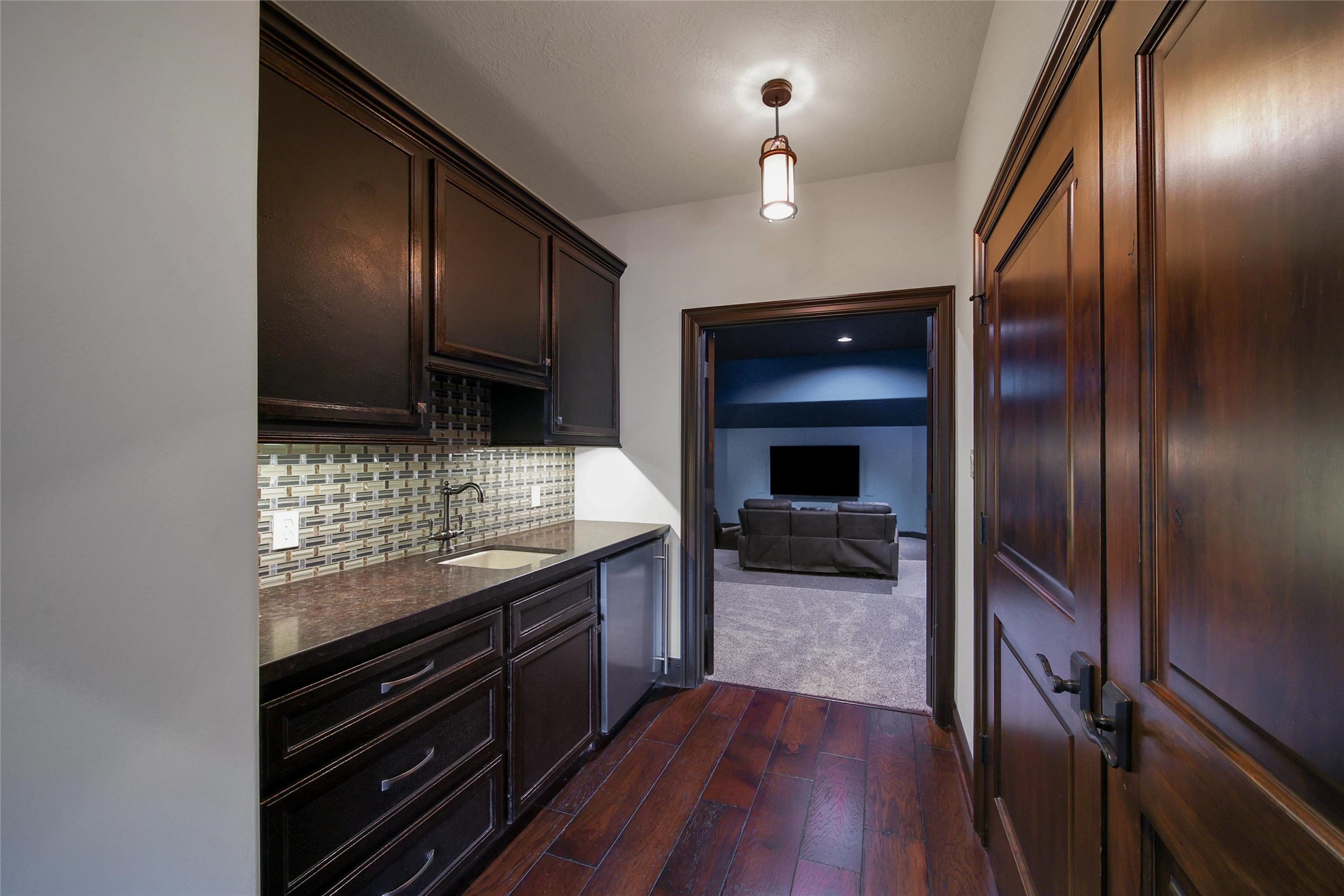 2 Highclere Park Drive Spring, TX 77379 - Photo 25 of 50 Conveniently located between the game room and home theater, this stylish wet bar and snack center is perfect for effortless entertaining. Featuring rich cabinetry, a sleek under-mount sink, mosaic tile backsplash, under-cabinet lighting, and a beverage fridge—everything you need for movie nights, game days, or casual gatherings.