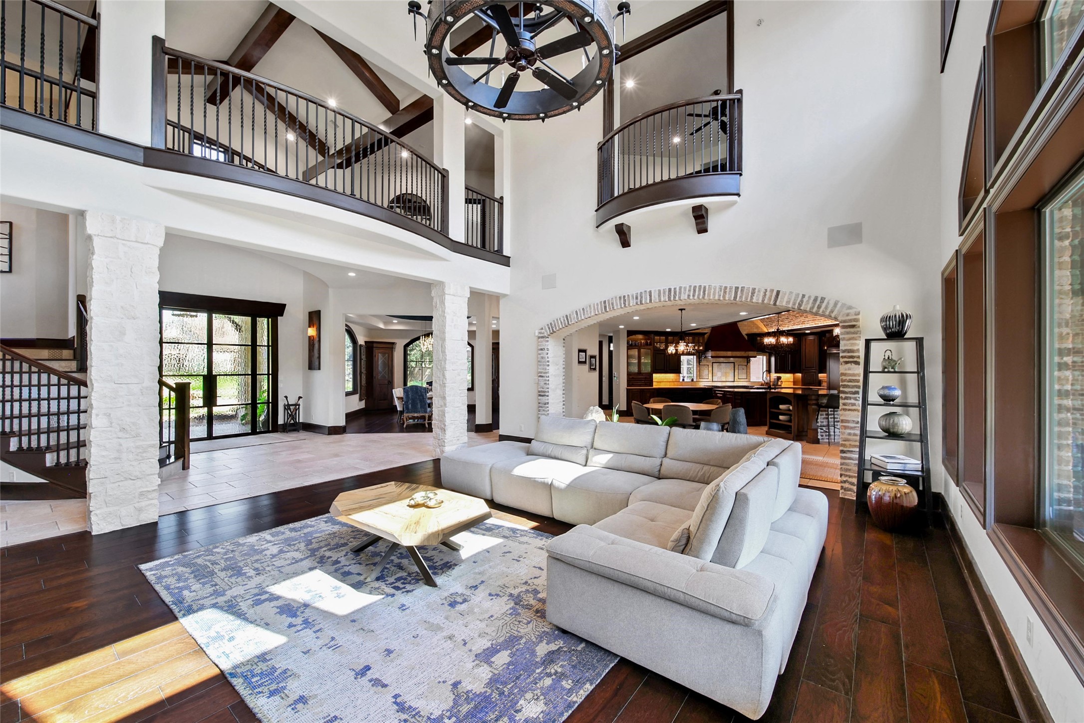 2 Highclere Park Drive Spring, TX 77379 - Photo 6 of 50 This soaring two-story family room offers an open yet defined layout, where stone columns, hardwood floors, and a dramatic brick archway create seamless flow to the kitchen and living areas—perfect for both everyday living and entertaining.