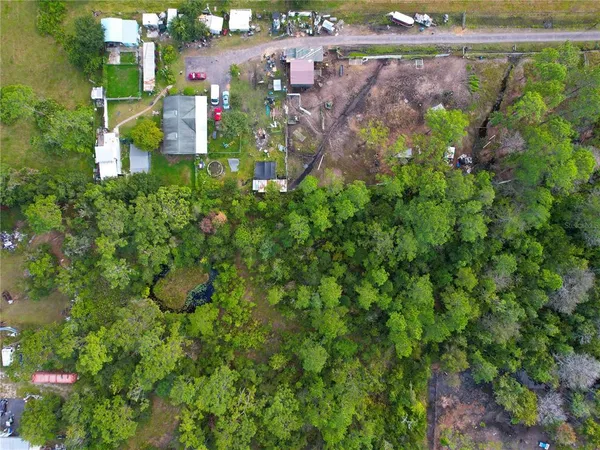 an aerial view of residential house with outdoor space and trees all around