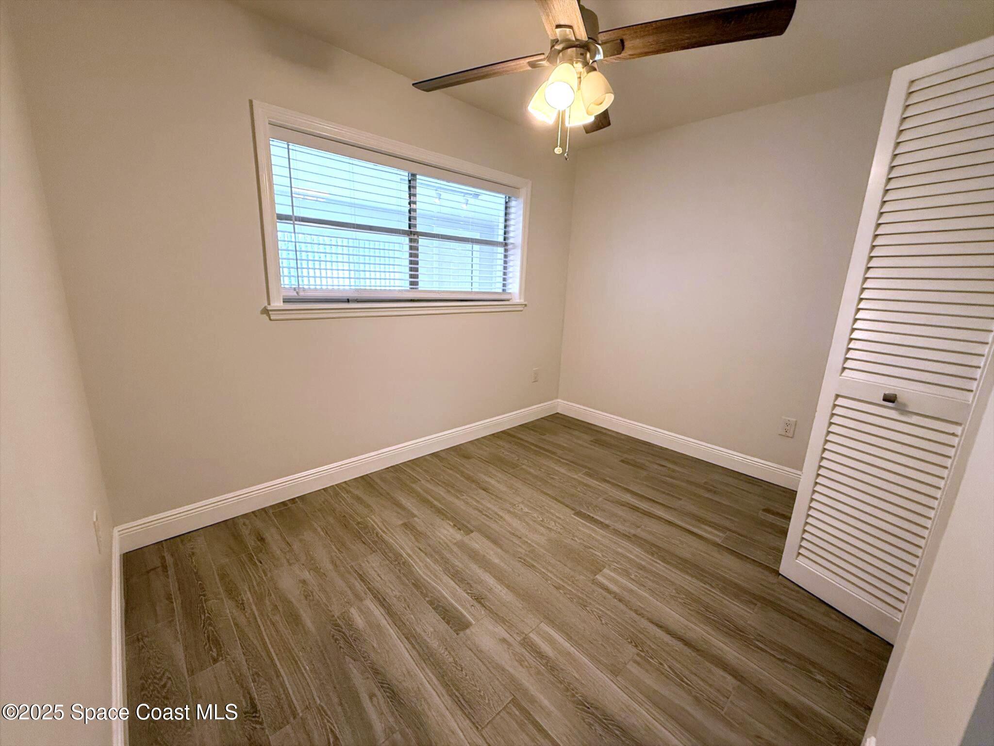 2801 Lorna Drive Melbourne, FL 32935 - Photo 13 of 25 an empty room with wooden floor fan and windows