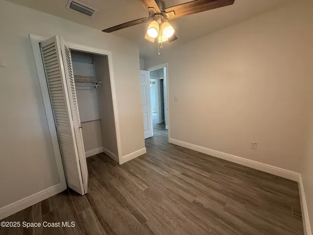 an empty room with wooden floor cabinet and windows
