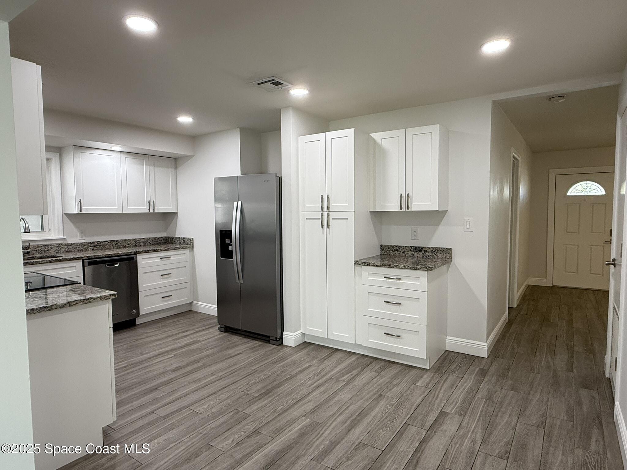 2801 Lorna Drive Melbourne, FL 32935 - Photo 17 of 25 a kitchen with white cabinets and stainless steel appliances