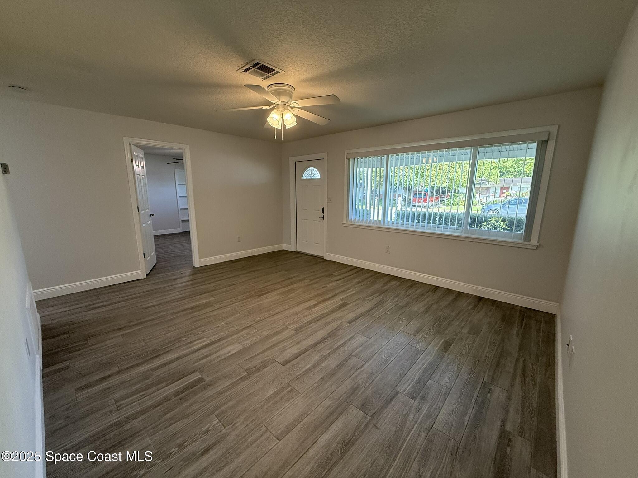 2801 Lorna Drive Melbourne, FL 32935 - Photo 4 of 25 a view of an empty room with wooden floor and a window