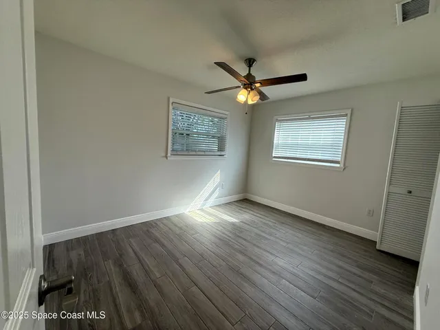 a view of empty room with wooden floor and fan