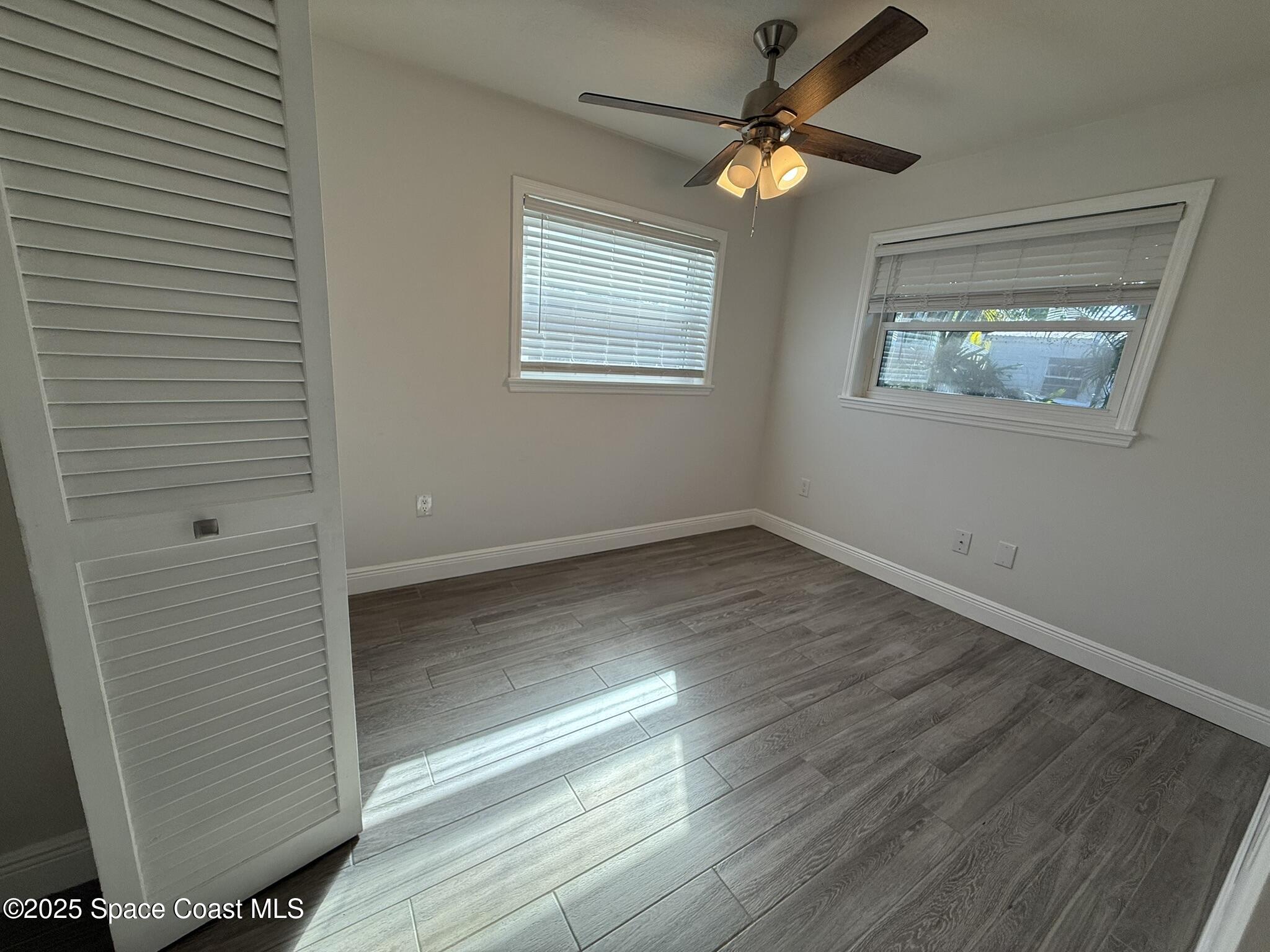 2801 Lorna Drive Melbourne, FL 32935 - Photo 10 of 25 an empty room with wooden floor chandelier fan and windows