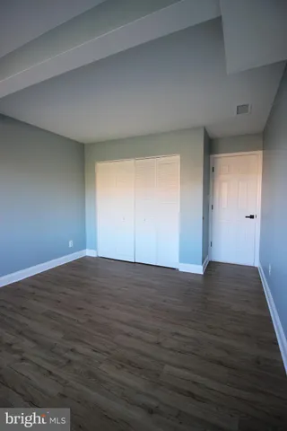 a view of an empty room with wooden floor and window