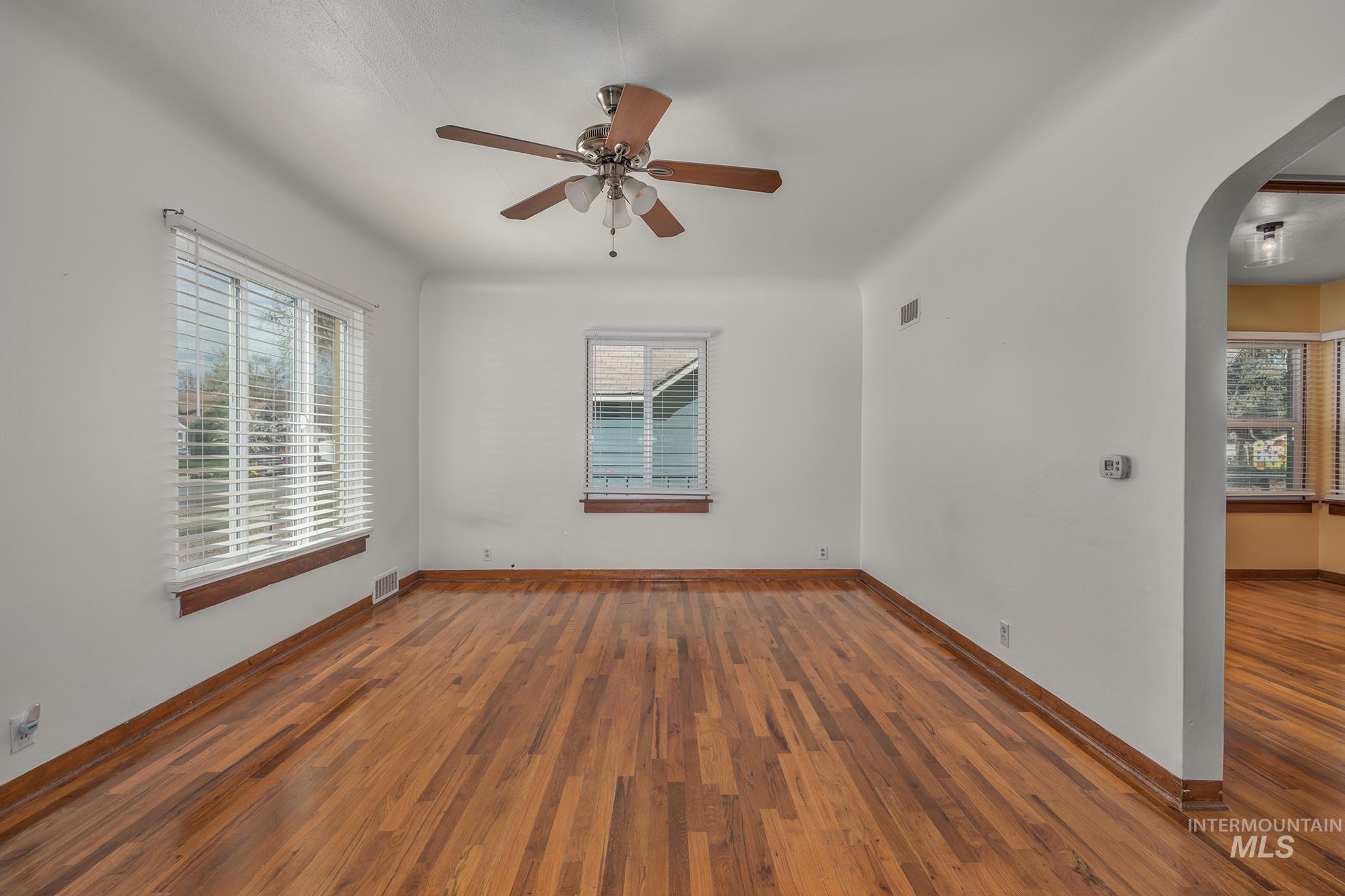 1016 West 5th Street Weiser, ID 83672 - Photo 2 of 36 Empty room featuring arched walkways, wood-type flooring, and ceiling fan