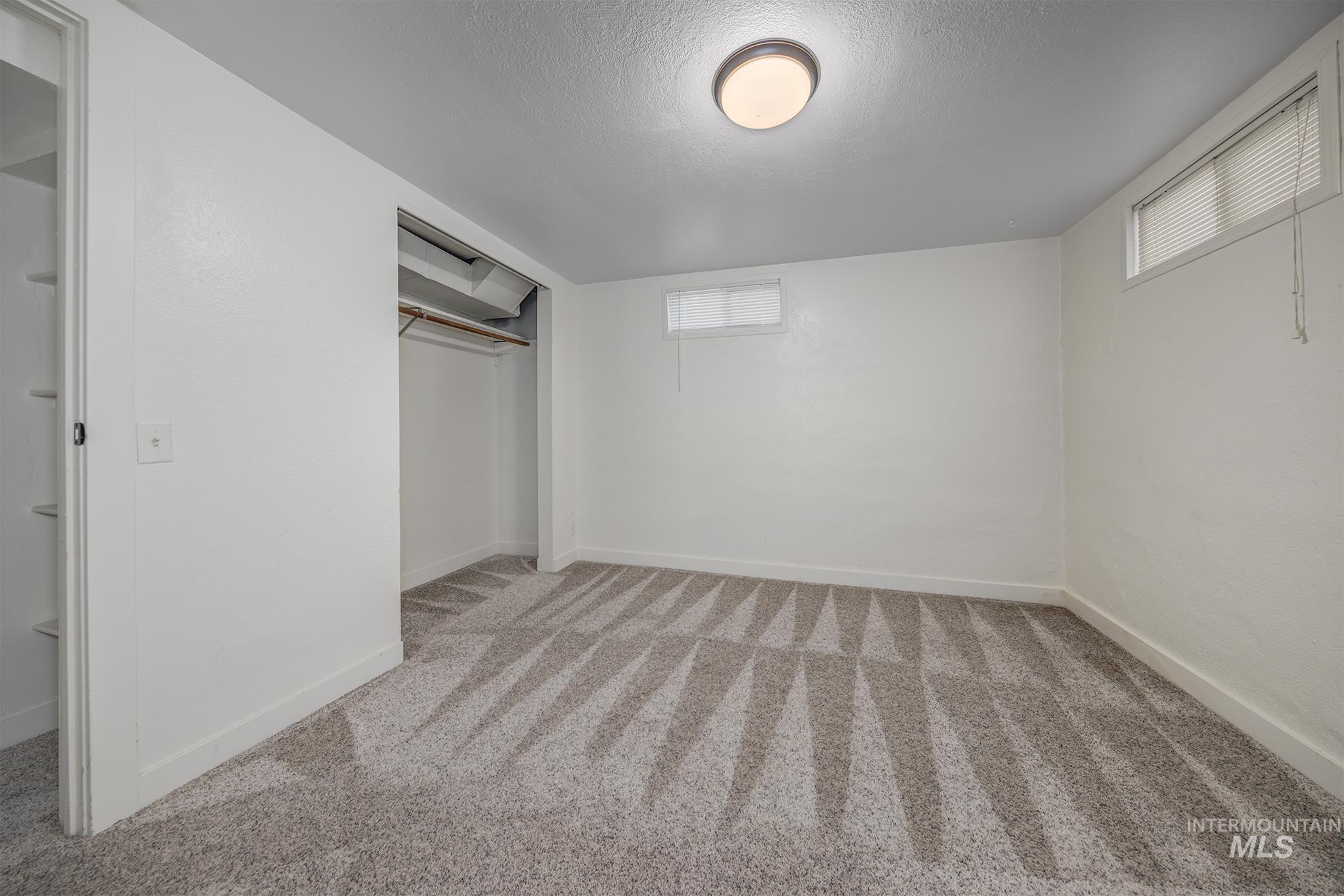 1016 West 5th Street Weiser, ID 83672 - Photo 21 of 36 Unfurnished bedroom with a closet, light colored carpet, multiple windows, and a textured ceiling