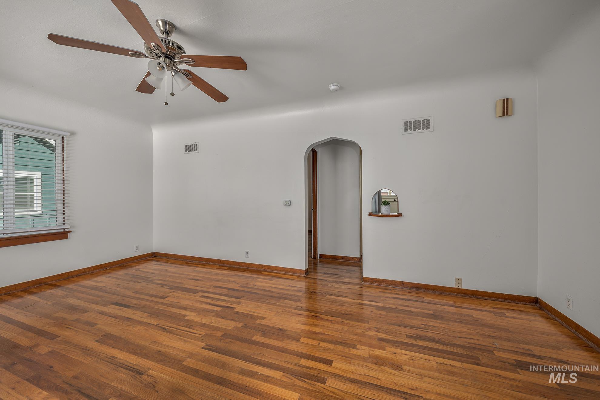 1016 West 5th Street Weiser, ID 83672 - Photo 3 of 36 Unfurnished room featuring arched walkways, wood finished floors, and ceiling fan
