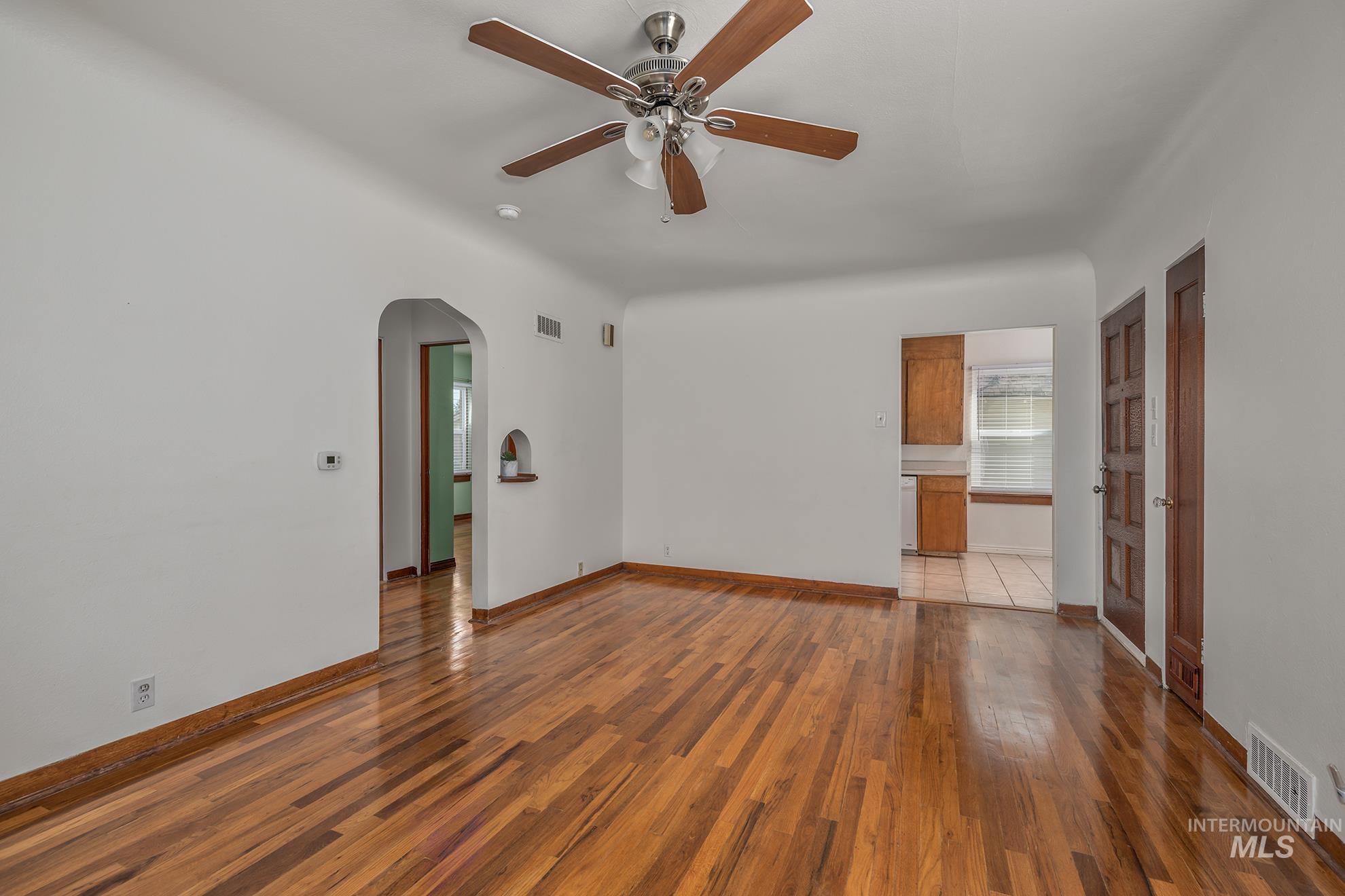 1016 West 5th Street Weiser, ID 83672 - Photo 4 of 36 Unfurnished room featuring wood-type flooring, ceiling fan, and arched walkways