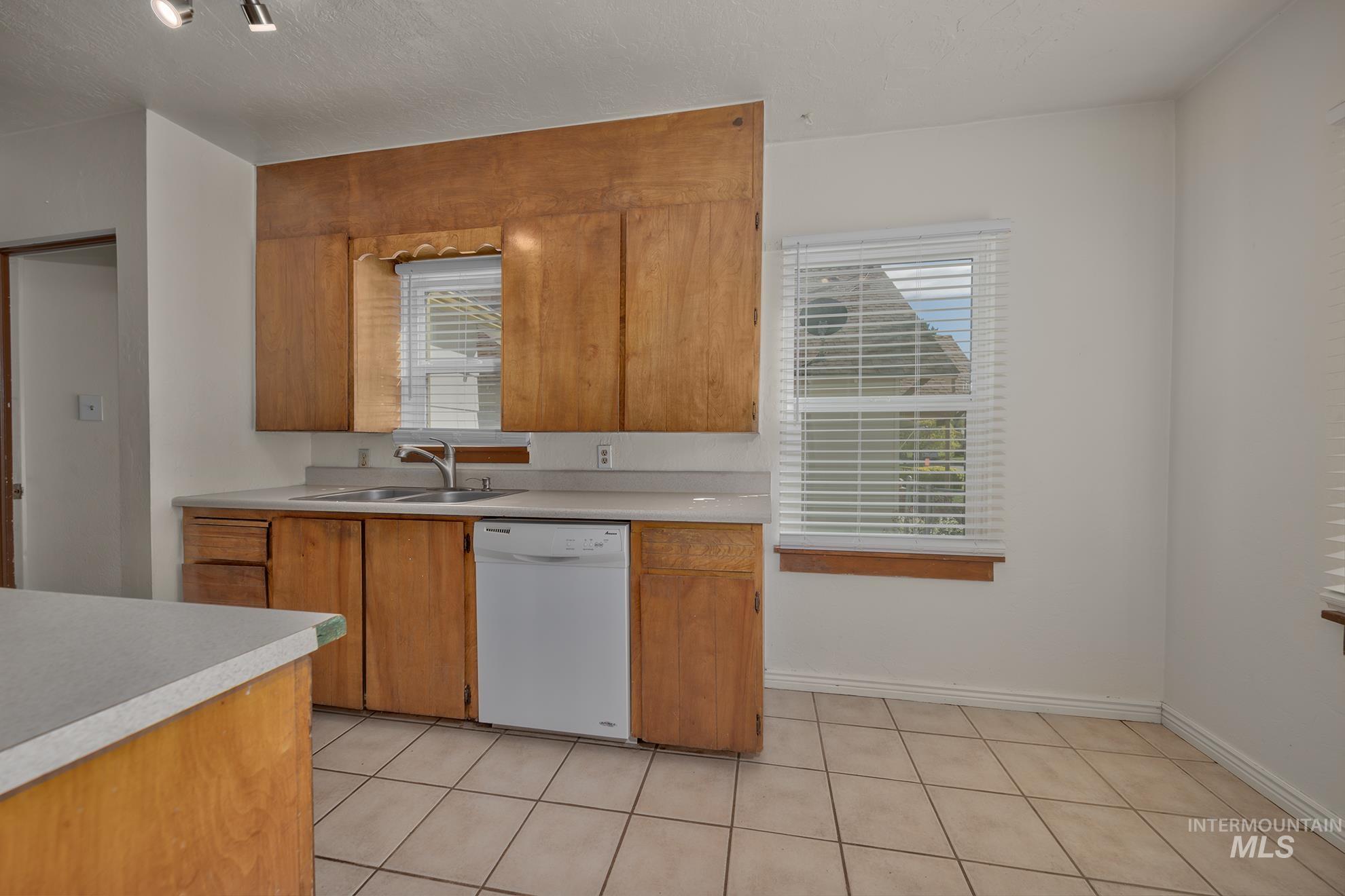 1016 West 5th Street Weiser, ID 83672 - Photo 6 of 36 Kitchen with light countertops, dishwasher, wood finish cabinets, a textured ceiling, and light tile patterned floors