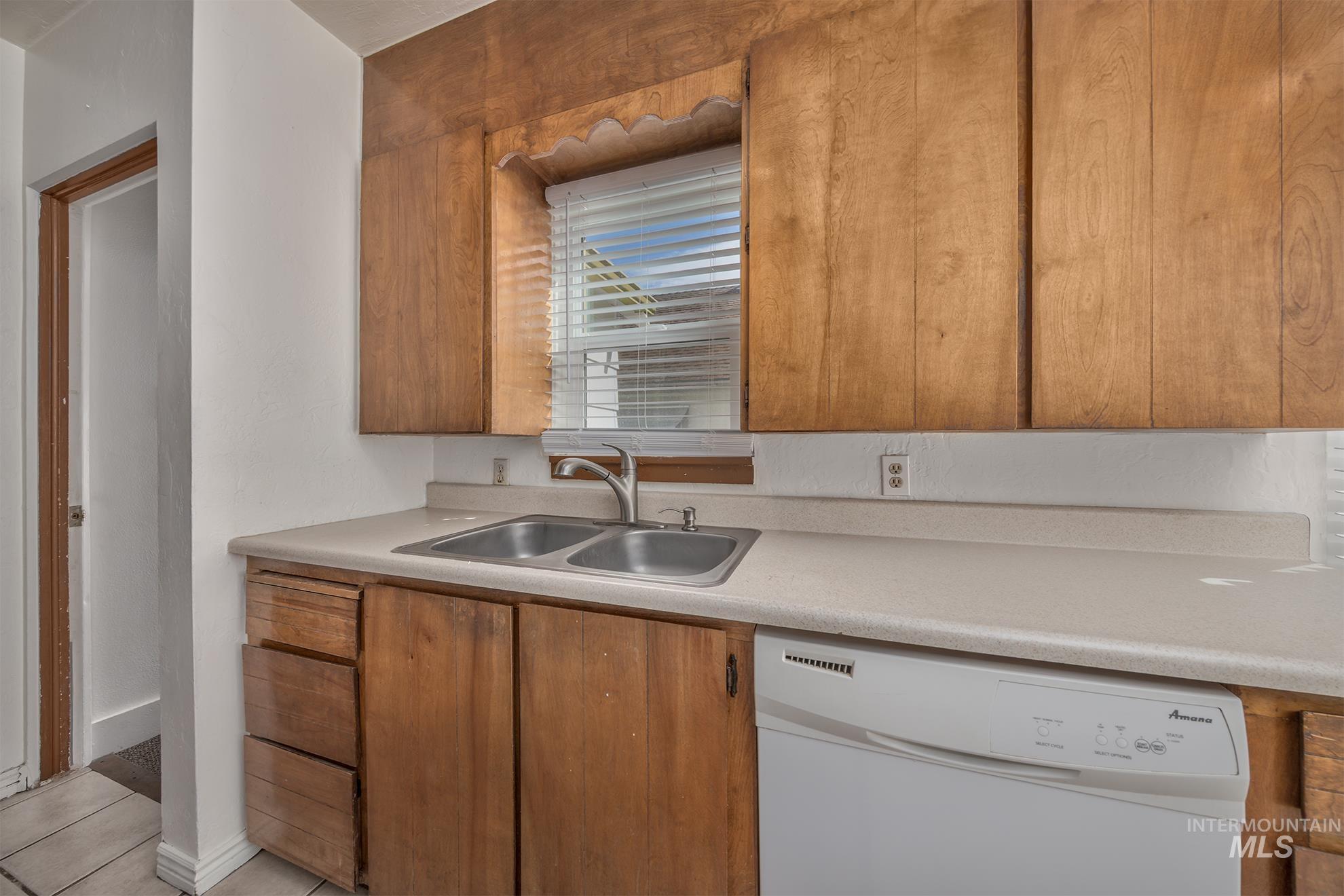 1016 West 5th Street Weiser, ID 83672 - Photo 7 of 36 Kitchen with white dishwasher, wood finish cabinets, light countertops, and light tile patterned floors