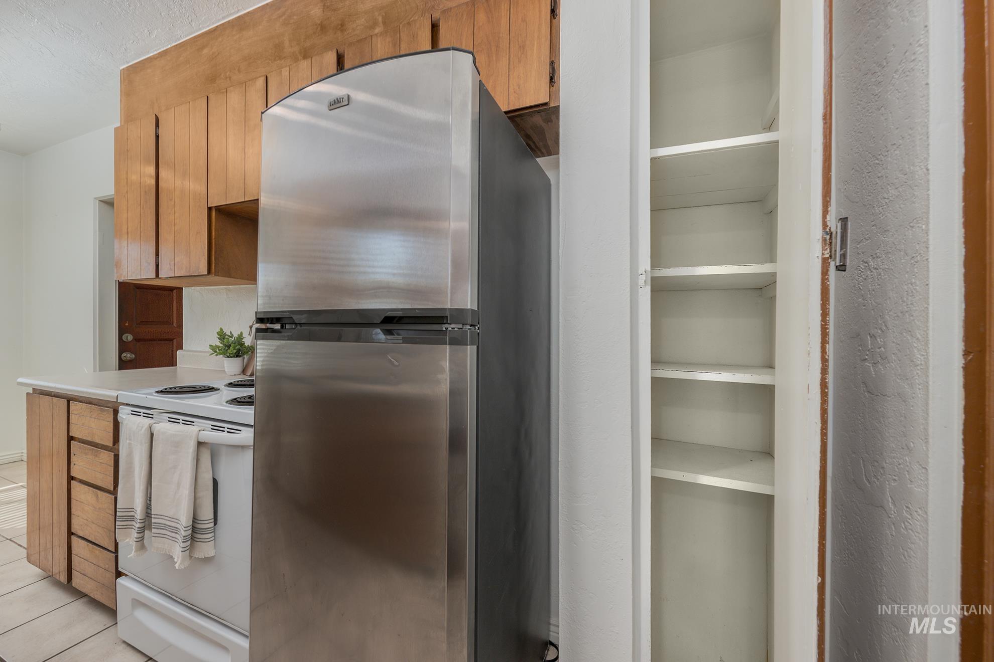 1016 West 5th Street Weiser, ID 83672 - Photo 9 of 36 Kitchen featuring freestanding refrigerator, white range with electric cooktop, wood finish cabinets, and light countertops