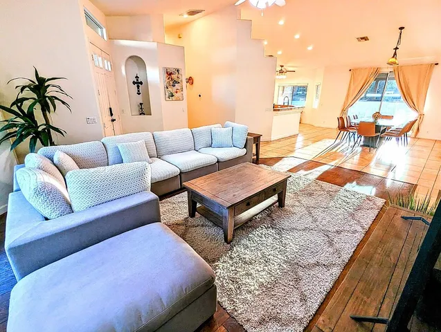 a living room with furniture and a dining table with wooden floor