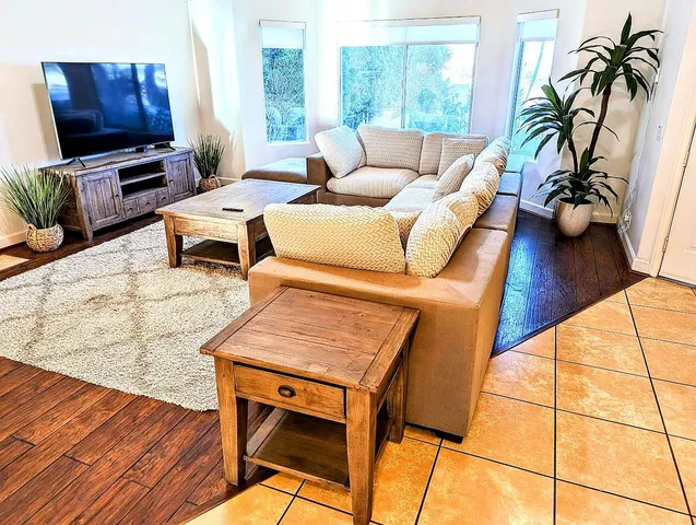 a living room with furniture a wooden floor and next to a window