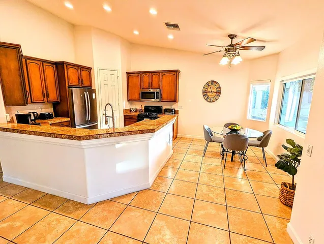 a living room with stainless steel appliances furniture a rug and a kitchen view