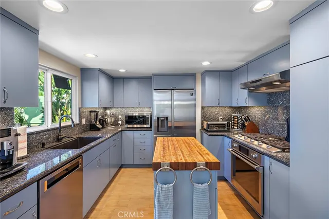 a kitchen with stainless steel appliances granite countertop a sink stove and refrigerator